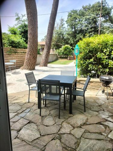 - une table et des chaises sur une terrasse en pierre dans l'établissement Maison à 50 M de la plage sous les pins, à Saint-Brévin-les-Pins