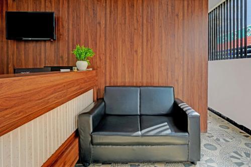 a leather chair in a waiting room with a tv at Hotel O New Shelton Suites in Bengaluru