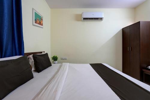 a bedroom with a large bed with a blue curtain at Hotel O New Shelton Suites in Bengaluru
