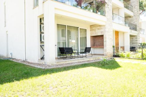 a house with two chairs and a table in a yard at Gjiri i Lalzit - San Pietro - Leta's Premium Apartments in Lalzit Bay
