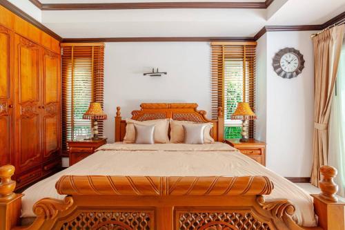 a bedroom with a large wooden bed and two lamps at Luxury Iconic Royal Boat Pool Villa North Pattaya in Pattaya Central