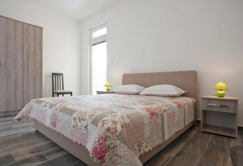 a bedroom with a bed and a chair and a window at Apartmani Agape in Petrovac na Moru