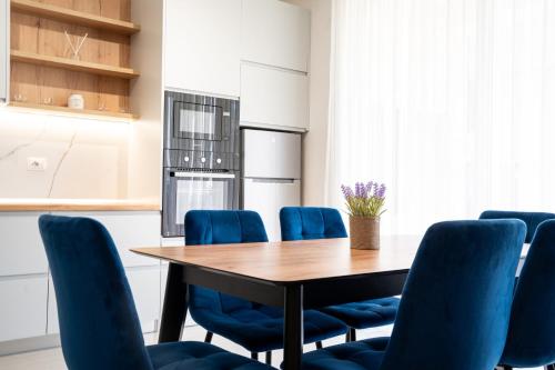a dining room with a table and blue chairs at Gjiri i Lalzit - San Pietro - Leta's Premium Apartments in Lalzit Bay