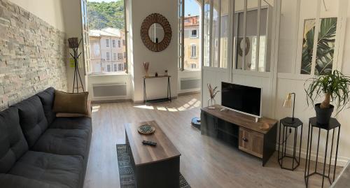 a living room with a couch and a tv at Le Charme d'Anduze in Anduze