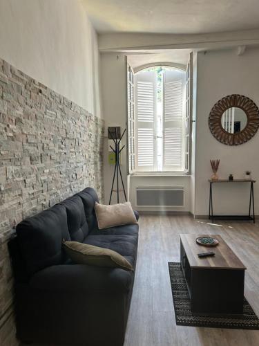 a living room with a black couch and a brick wall at Le Charme d'Anduze in Anduze