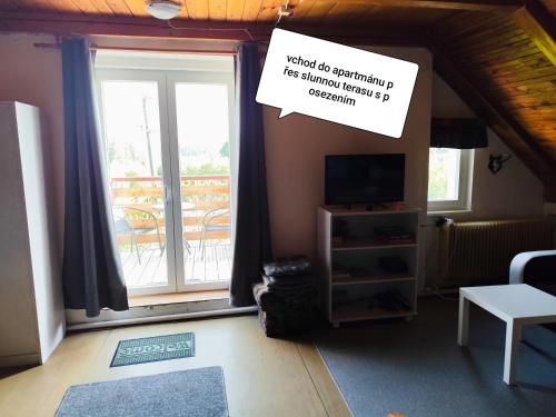 a living room with a window and a sign at Apartmán u lesa u Adršpachu in Jívka