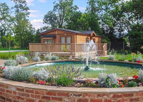 a log cabin with a fountain in a garden at York House Holiday Park in Thirsk