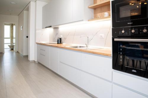 a white kitchen with a sink and a microwave at Gjiri i Lalzit - San Pietro - Leta's Premium Apartments in Lalzit Bay