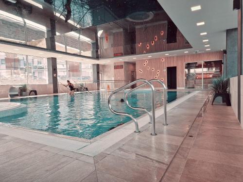 ein Schwimmbad in einem Gebäude mit einer Person im Hintergrund in der Unterkunft Rewalove Apartamenty - apartament typu studio in Rewal