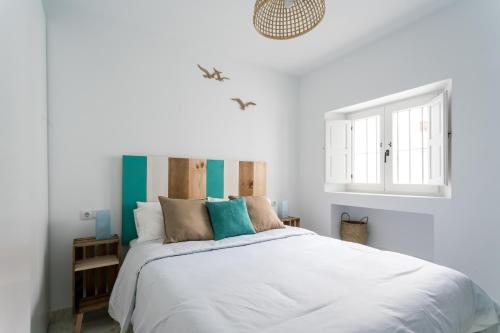 een slaapkamer met een groot wit bed met blauwe accenten bij Fantástico ático en el casco antiguo en a la playa in Cádiz