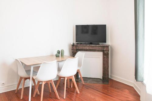 une table à manger avec des chaises blanches et une télévision à écran plat dans l'établissement Confort aux Portes de Paris - 5 pers near Subway, à Aubervilliers