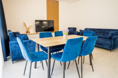 a dining room with a table and blue chairs at Gjiri i Lalzit - San Pietro - Leta's Premium Apartments in Lalzit Bay