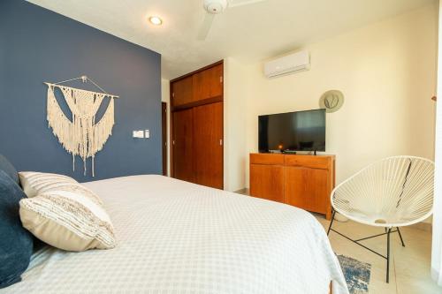 a bedroom with a white bed and a tv at Hermoso Departamento En la Playa in Chicxulub