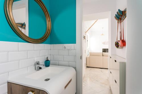 een badkamer met een witte wastafel en een spiegel bij Fantástico ático en el casco antiguo en a la playa in Cádiz