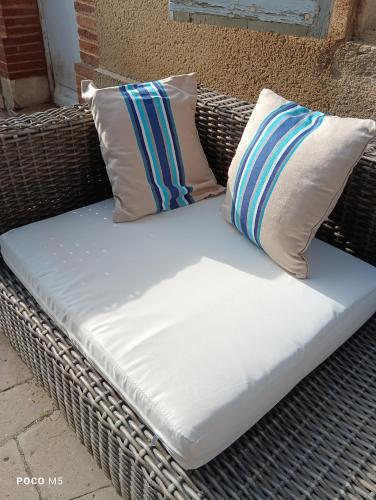 two pillows sitting on top of a wicker bench at Artbnb in Lézat-sur-Lèze