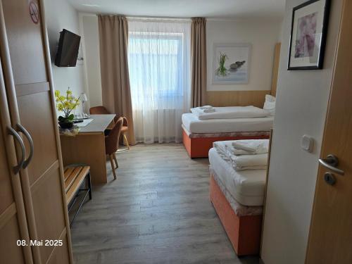 a hotel room with two beds and a desk at Hotel Ackermann in Riedstadt