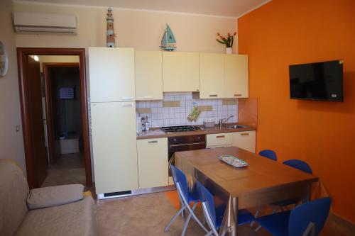 a kitchen with white cabinets and a table with blue chairs at Casa Vacanze Sicilia Tirrena in Finale