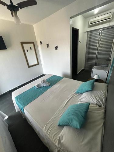 a bedroom with a large bed with blue pillows at POUSADA MAORI Boiçucanga in Boicucanga