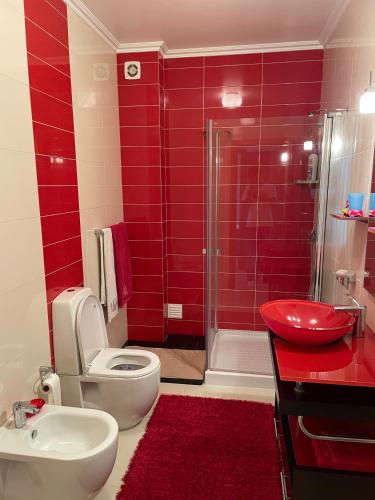 a red bathroom with a toilet and a sink at Oásis da Praia in Bicas
