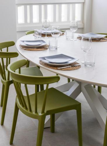 a white table with green chairs and plates and wine glasses at Vacation Home Bonaire in Kralendijk