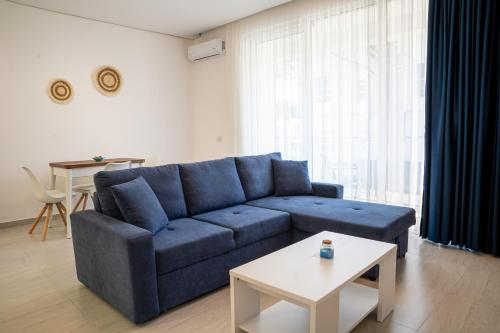 a living room with a blue couch and a table at Gjiri i Lalzit - San Pietro - Leta's Premium Apartments in Lalzit Bay