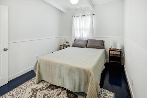 een witte slaapkamer met een bed en twee nachtkastjes bij Papa John's in St Pete Beach