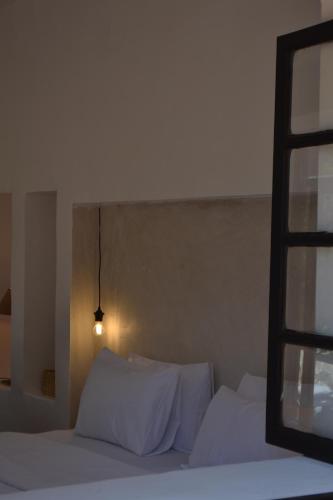 a bedroom with a bed with white sheets and a window at Villa Quince in Ouirgane