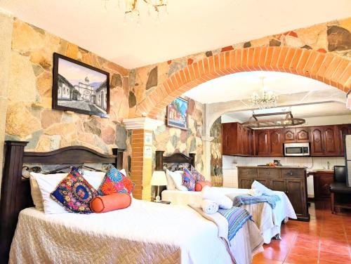 a bedroom with two beds and a stone wall at Casa Quetzalli, La Recolección in Antigua Guatemala