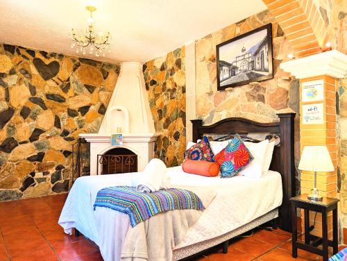 a bedroom with a bed and a stone wall at Casa Quetzalli, La Recolección in Antigua Guatemala