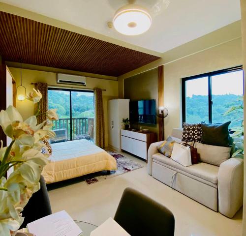a bedroom with a bed and a couch and a tv at Alpine Villas Greens Staycation at Crosswinds Tagaytay in Tagaytay