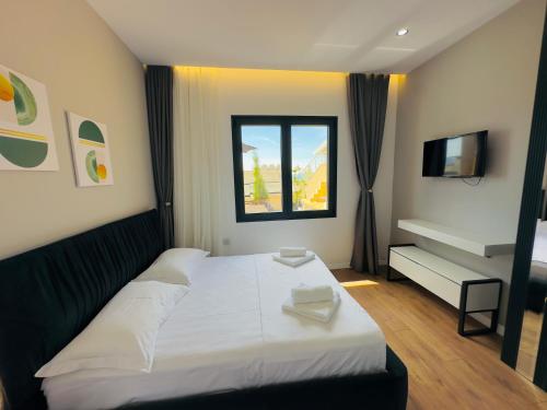 a bedroom with a white bed and a window at Seafront Penthouse with Sunset Views & Jacuzzi in Vlorë