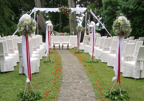 an aisle with white chairs and tables with flowers at Castello Di Spessa - Residenze d'epoca in Capriva del Friuli