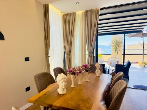 a dining room table with chairs and flowers on it at Seafront Penthouse with Sunset Views & Jacuzzi in Vlorë
