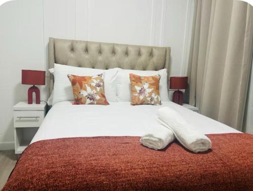 a large white bed with a red blanket and pillows at 4beds,3 bedrooms,Braai,Full kitchen in Tzaneen