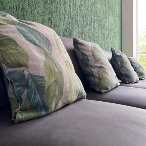 a couch with three pillows on top of it at Bonito departamento en privada con alberca in Cancún