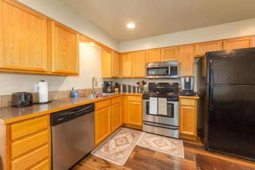 a kitchen with wooden cabinets and a black refrigerator at Spacious 3BR Family Retreat w Fire Pit BBQ Smart TVs & More in Spokane Valley
