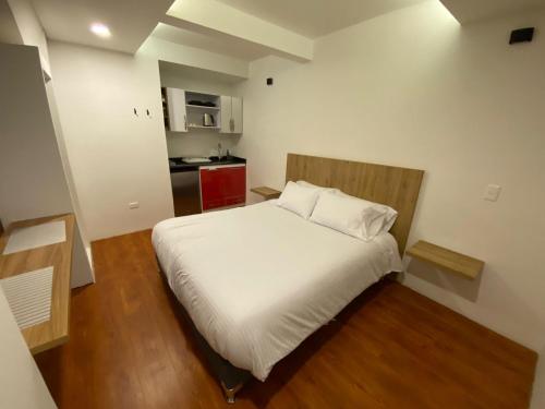 a small bedroom with a white bed and a kitchen at Apartaestudio comodo y central S3 - WiFi in Pasto