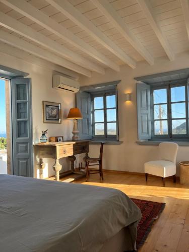 a bedroom with a bed and a desk and windows at A Patmos premium house in Chora in Patmos