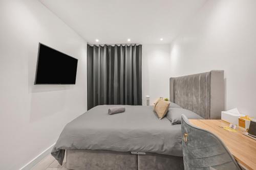 a bedroom with a bed and a television on the wall at Bricklane Apartment in London