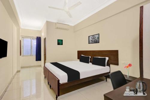 a bedroom with a bed and a table and a desk at Hotel O Jagadamba Junction in Visakhapatnam