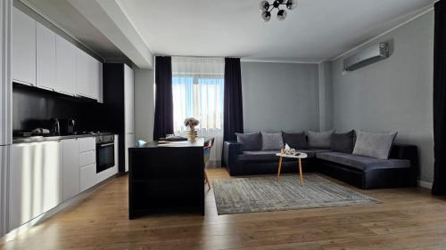 Una sala de estar con un sofá y una cocina. en Royal Apartments Otopeni DN, en Otopeni