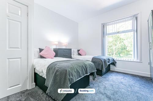 a bedroom with two beds and a window at Spacious 3 BR House in PR6 Free Parking & WiFi Sleeps 6 in Chorley