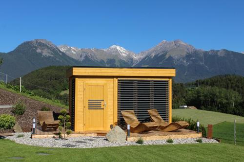 a wooden shed with chairs and mountains in the background at Landhaus Eiter in Arzl im Pitztal