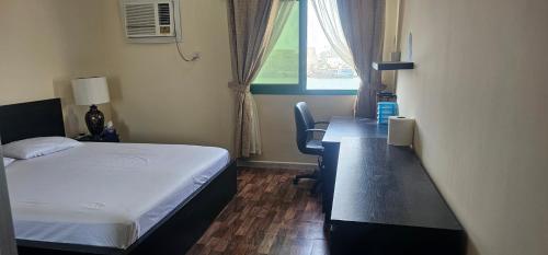a bedroom with a bed and a desk and a window at UrduEnglishFamilyApartmen in Sharjah