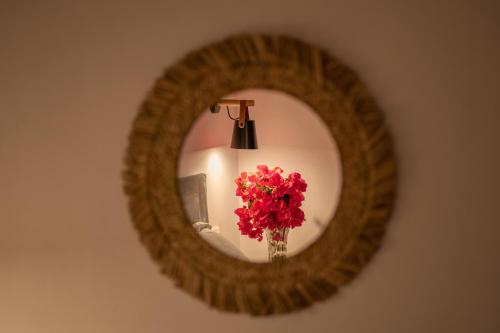 a mirror with a vase of red flowers and a lamp at Casa Luna in Patitiri