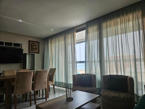 a living room with a dining table and a large window at La perle de Mehdia II, sea view in Plage de Mehdia