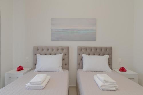 a bedroom with two beds with white sheets and red flowers at Casa Luna in Patitiri