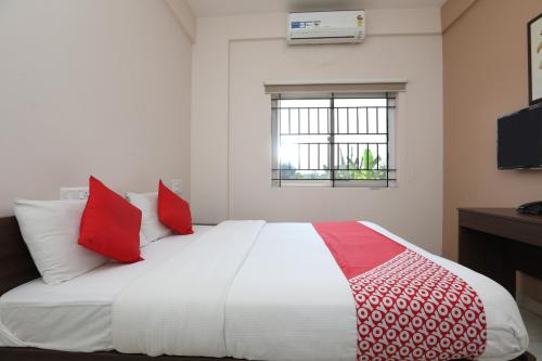 une chambre avec un grand lit blanc avec des oreillers rouges dans l'établissement Super Hotel O Indra Comforts, à Belagula