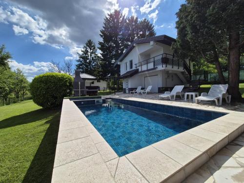 a swimming pool in front of a house at EmUm family cottage in Potkraj