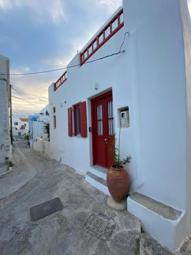 a white building with a red door and a potted plant at Agioutanti Spot in Kithnos